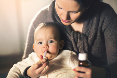 Mother giving medicine to baby at home