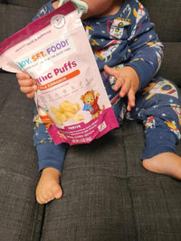 Child sitting on couch with a bag of RSF! Organic Puffs